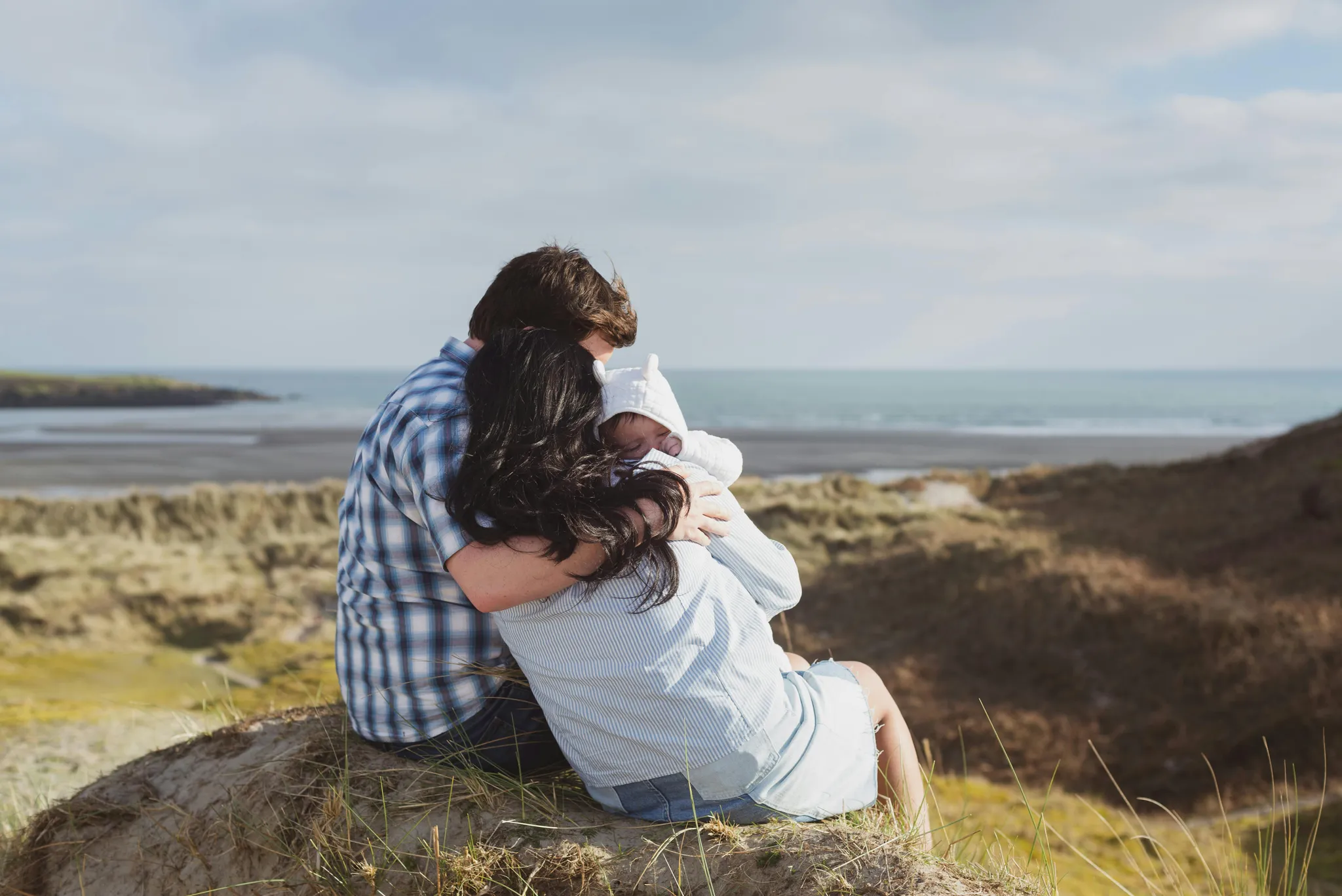 A family sitting on a peaceful hill giving each other a group hug