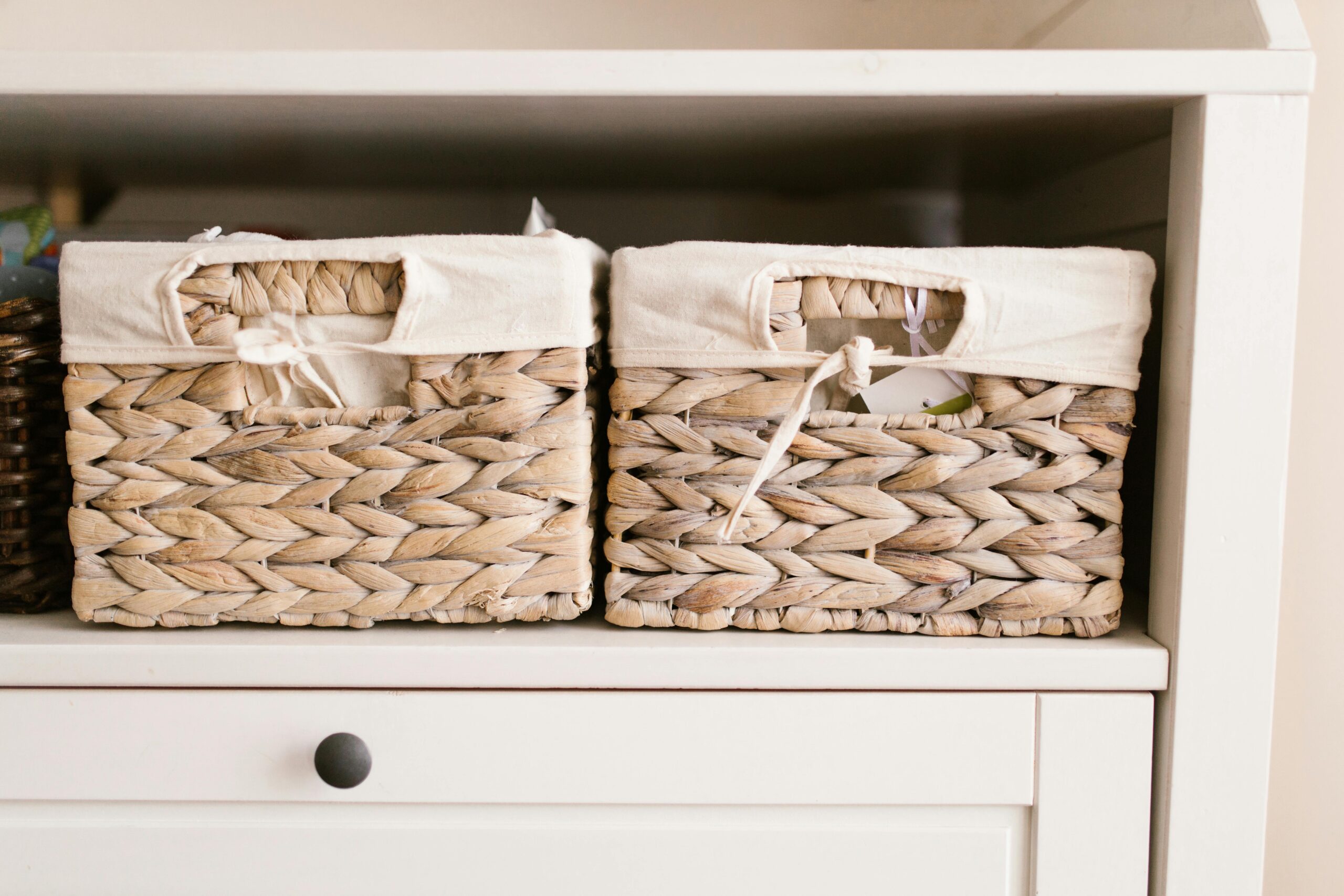 Two natural fiber baskets with cloth liners sit on a shelf